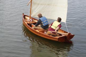 The slender lapstrake Sid skiff has a sprit rig