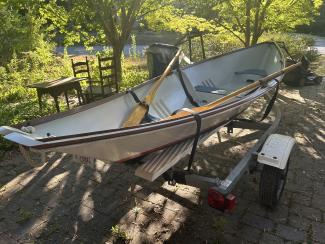 Custom wooden row boat, on trailer, starboard side from bow, oars in view