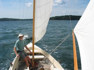 Rozinante Herreshoff design 1969, under sail view of bow and happy person