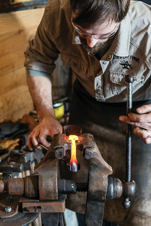 Med uses a vise-held spring swage to shape the head of the iron.