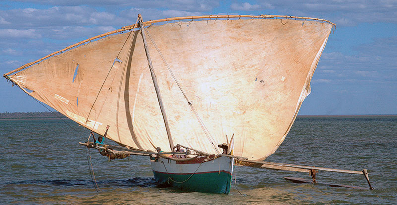 Cargo-carrying outrigger sailing canoe.