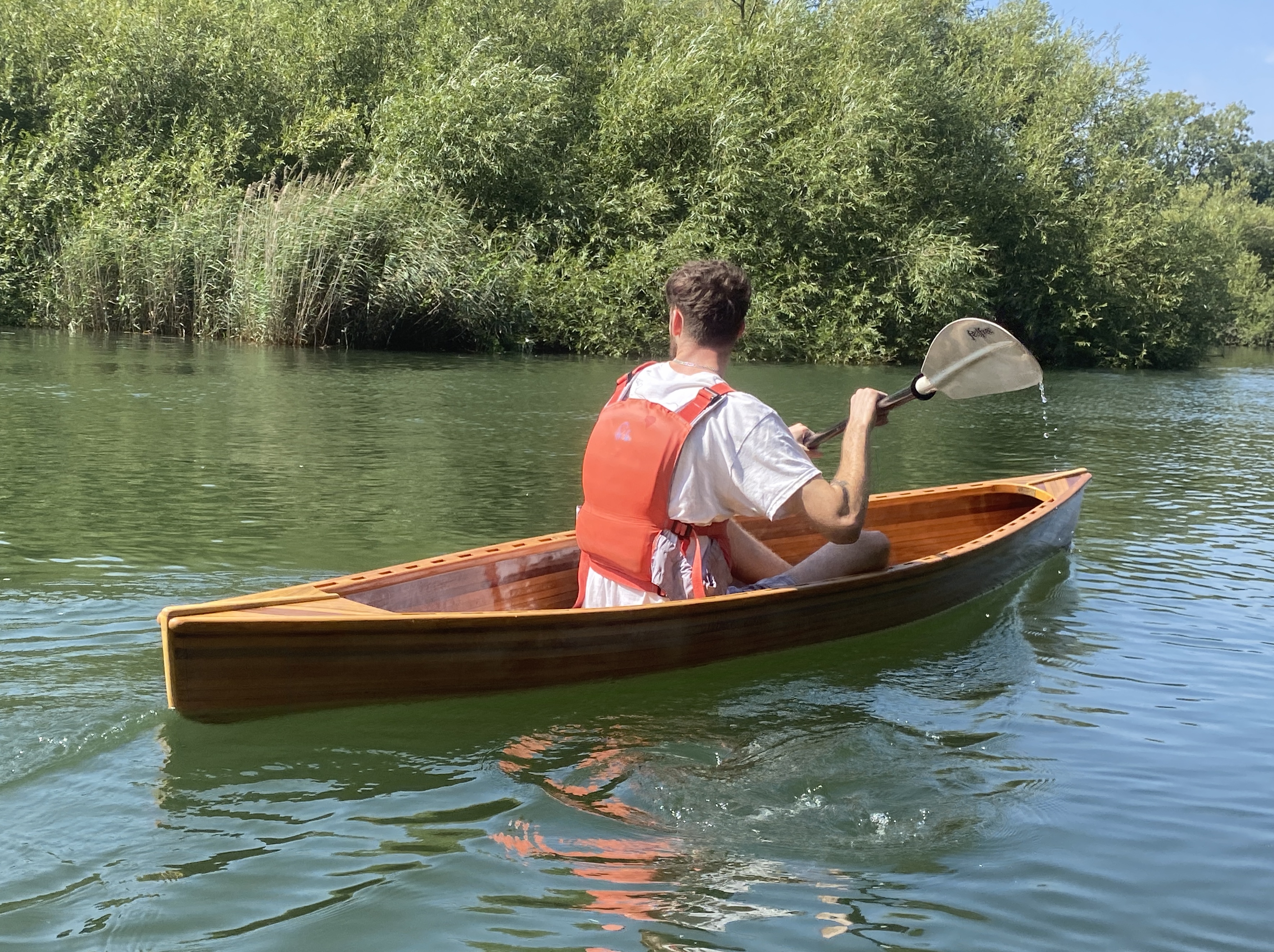 Tom paddling down a river, backdropped by trees. 