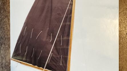 Gaff rigged wooden sailboat with trailer, undersail, port side bow view