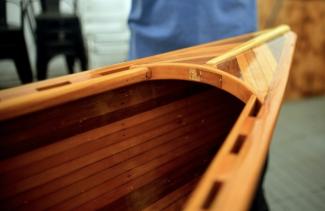 The breastbooks are decorated with the same cedar strips as the hull and have a raised ash highlight along the centre. The forward breasthook holds the stamped-brass nameplate. 