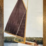Gaff rigged wooden sailboat with trailer, undersail, port side bow view